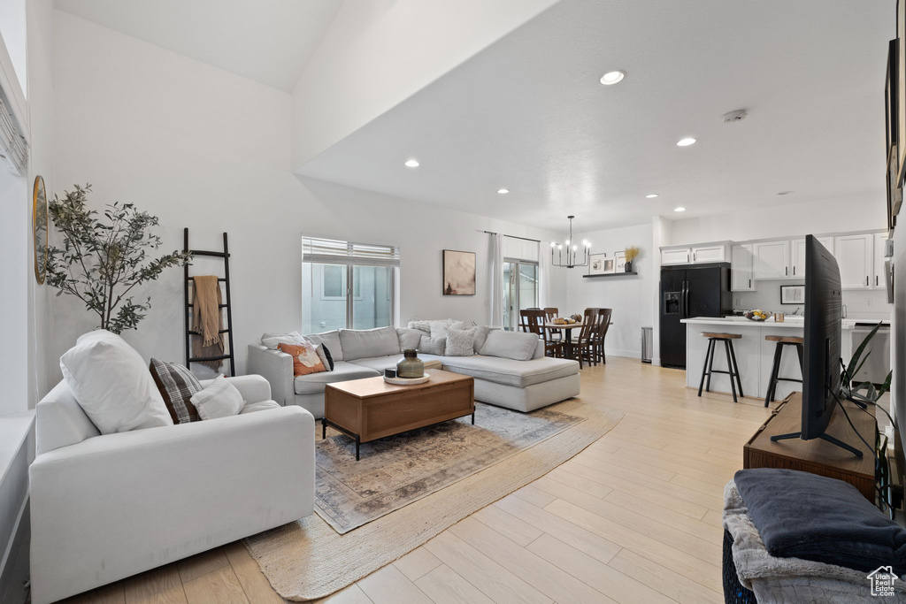 Living room with a high ceiling, a chandelier, and light hardwood / wood-style flooring