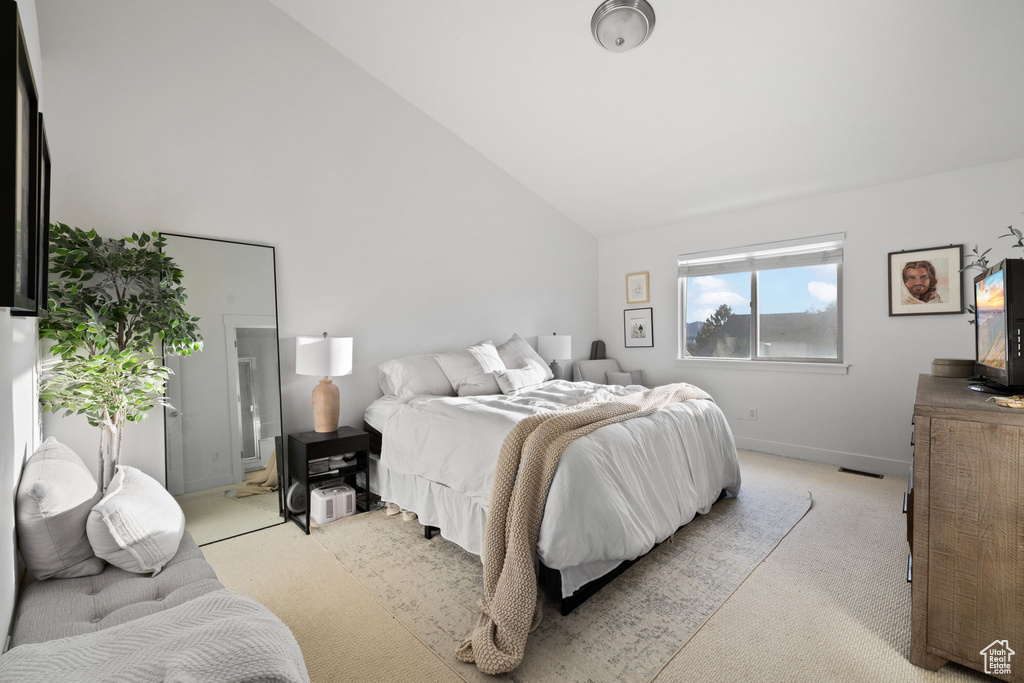 Bedroom featuring light colored carpet and high vaulted ceiling