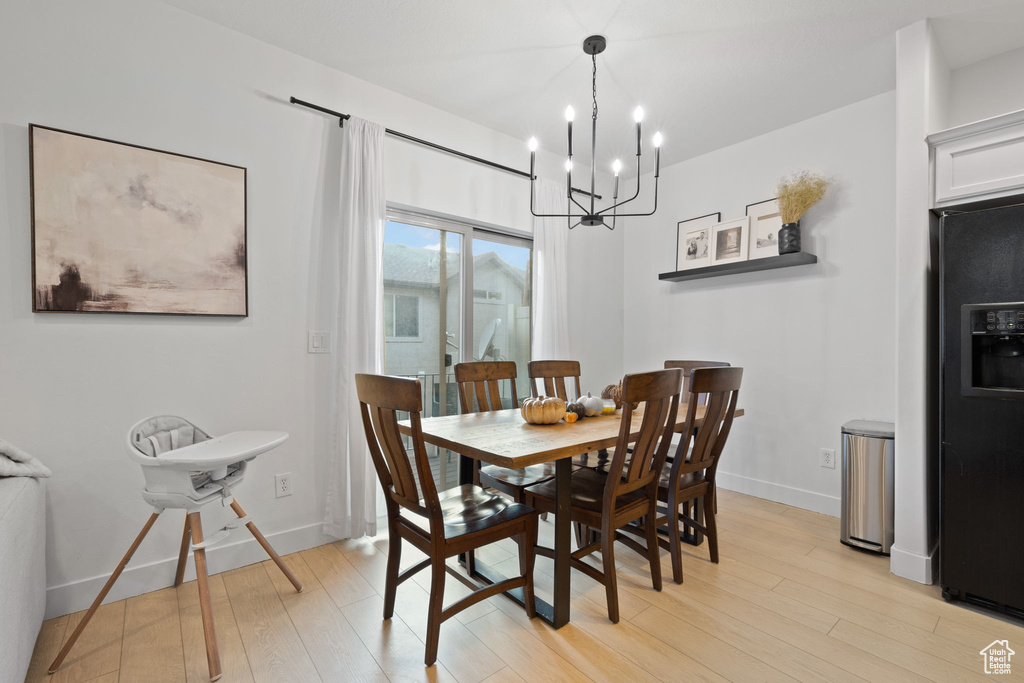 Dining room with light hardwood / wood-style flooring and a chandelier