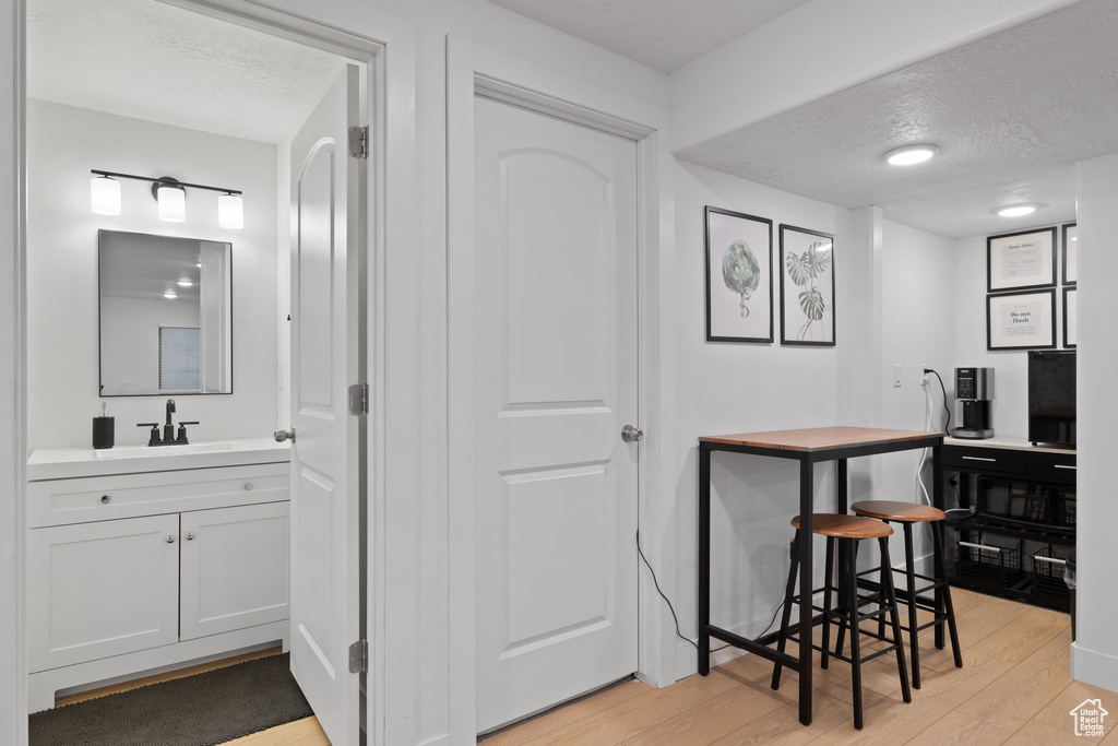 Interior space with white cabinets, light wood-type flooring, a textured ceiling, and sink