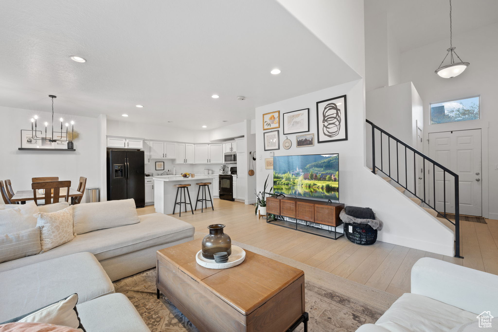 Living room featuring a high ceiling, a chandelier, and light hardwood / wood-style floors