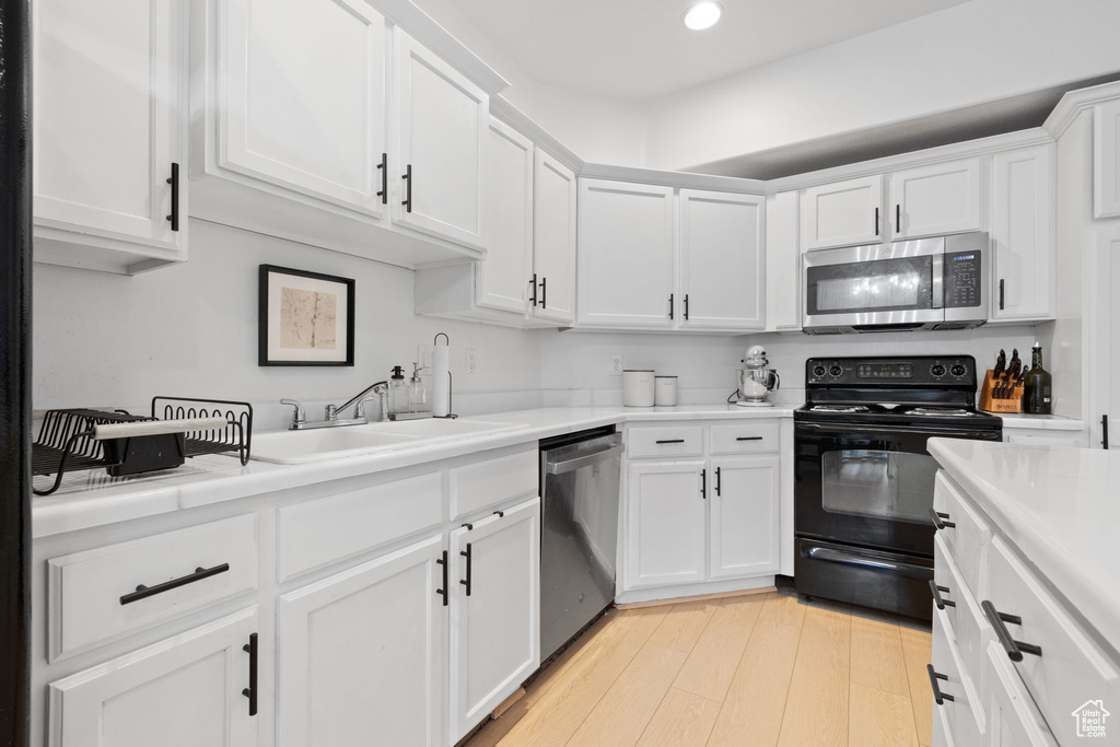 Kitchen featuring white cabinetry, light wood-type flooring, stainless steel appliances, and sink