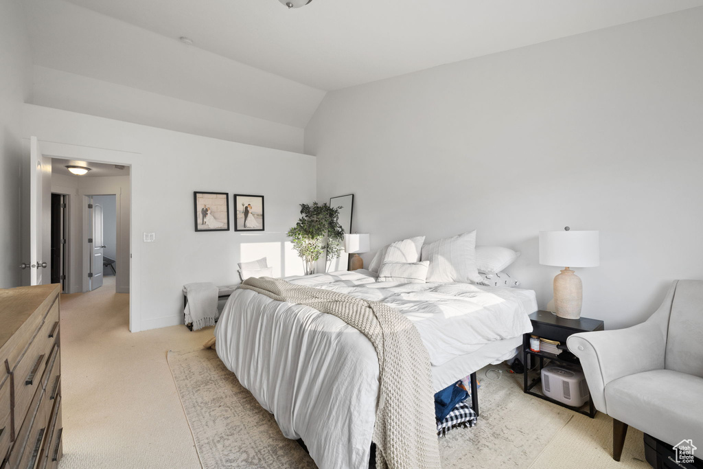 Bedroom with light colored carpet and vaulted ceiling