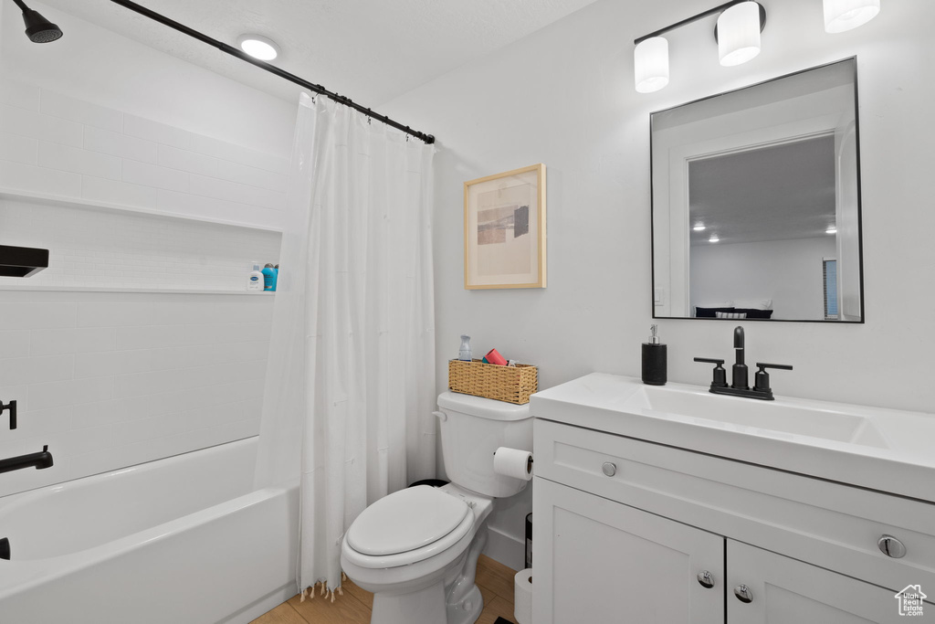 Full bathroom with vanity, shower / bath combination with curtain, and toilet