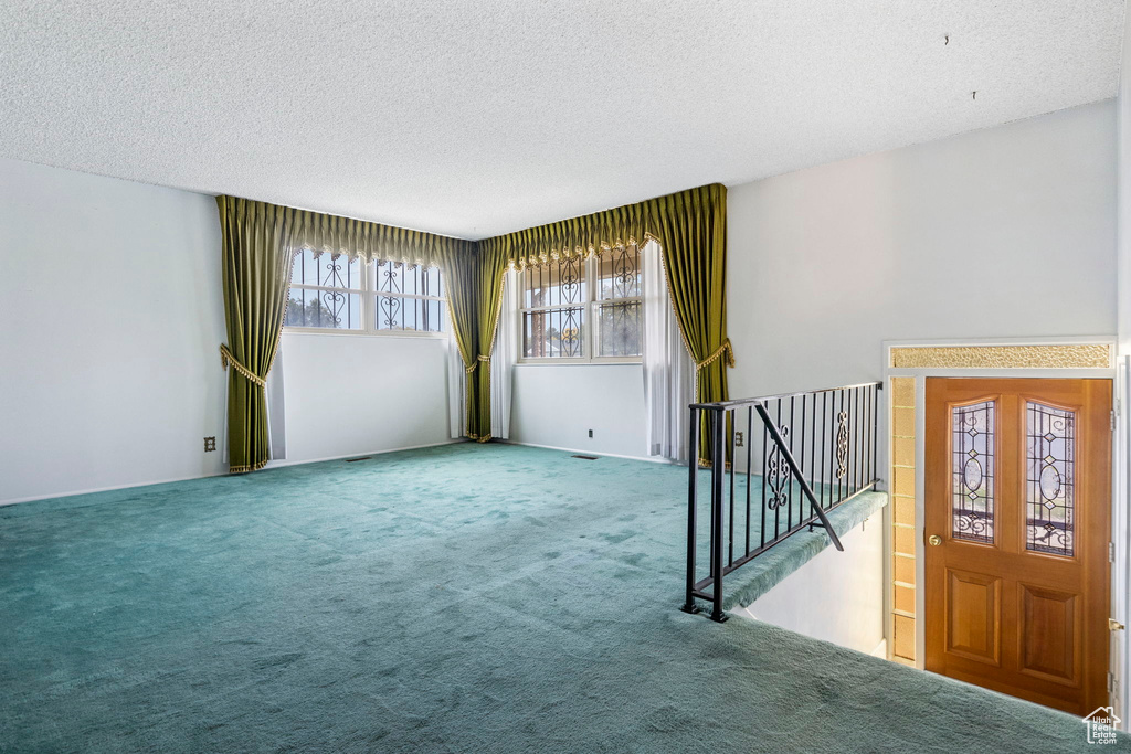 Carpeted empty room featuring a textured ceiling