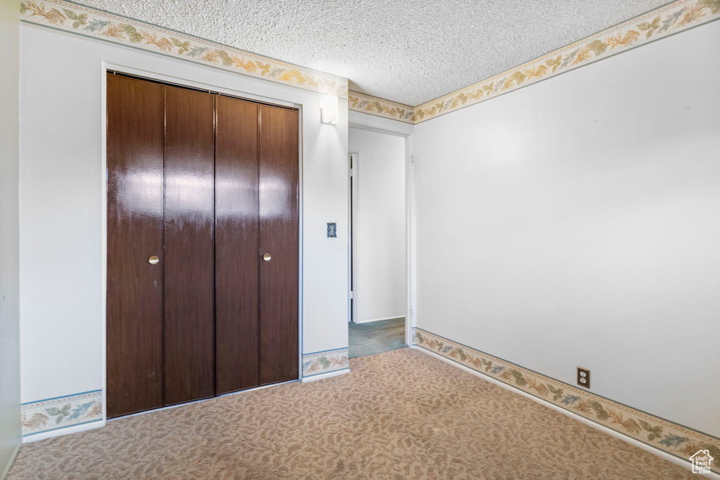 Unfurnished bedroom with a textured ceiling, a closet, and carpet