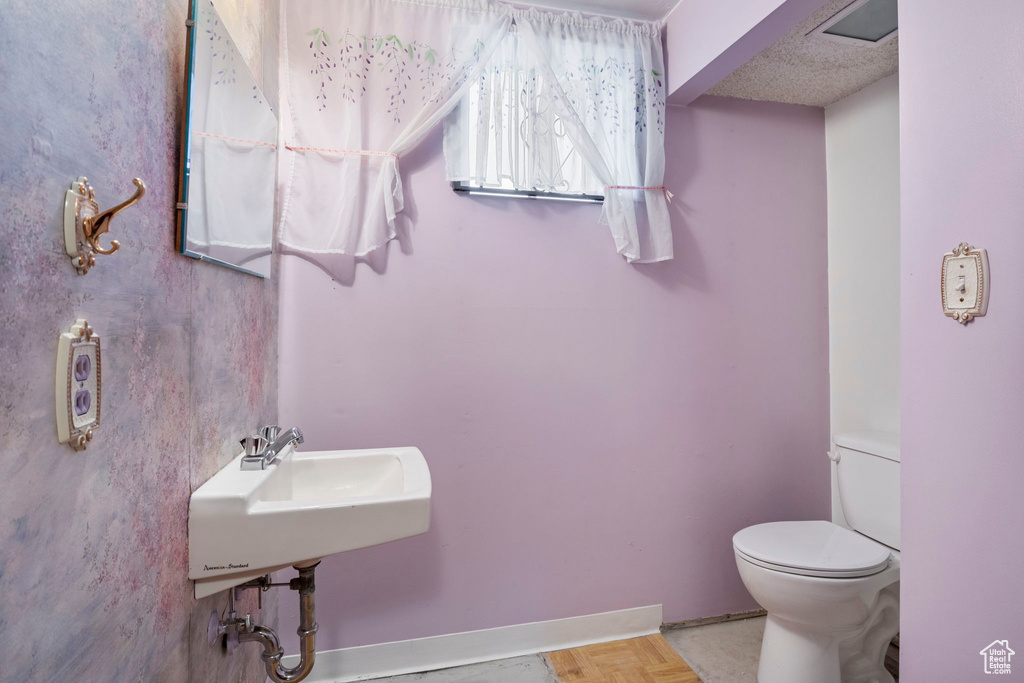 Bathroom with a textured ceiling, toilet, and sink