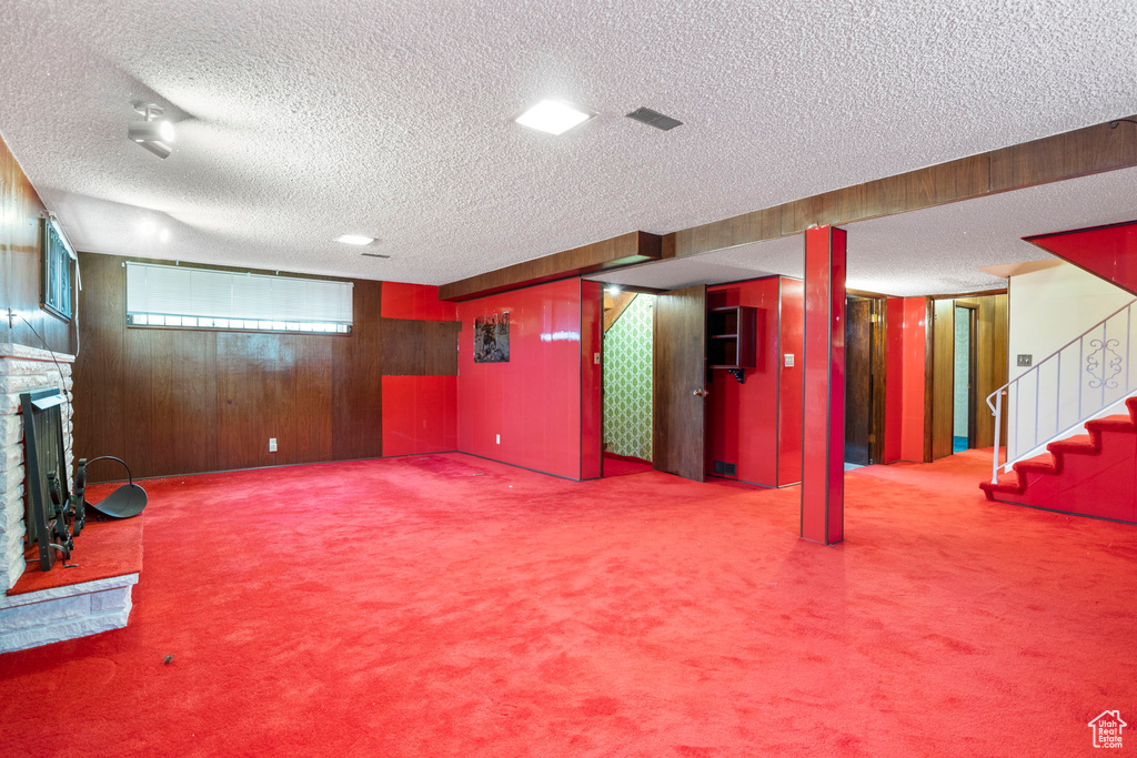 Basement featuring wood walls, a textured ceiling, and carpet floors