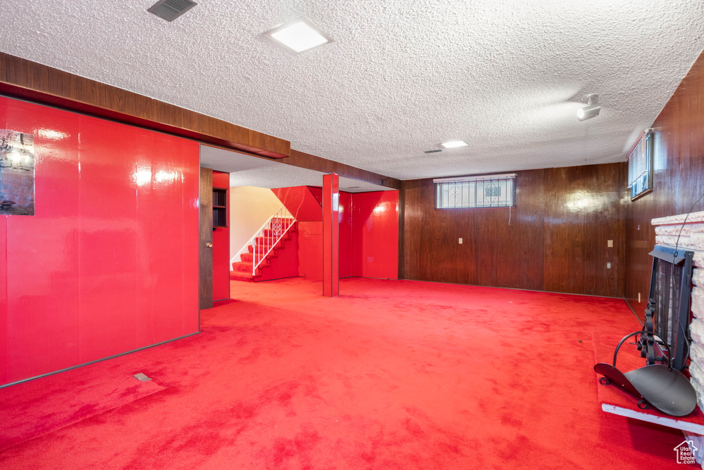 Basement featuring wood walls, light colored carpet, and a textured ceiling