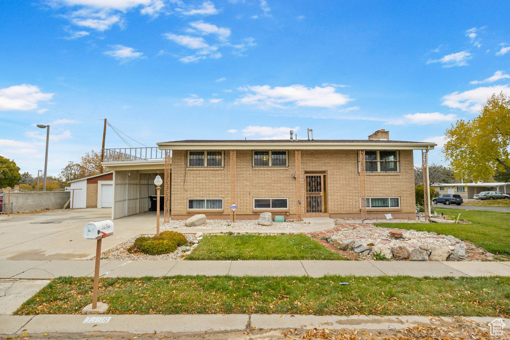 View of front facade featuring a garage, a carport, and a front yard