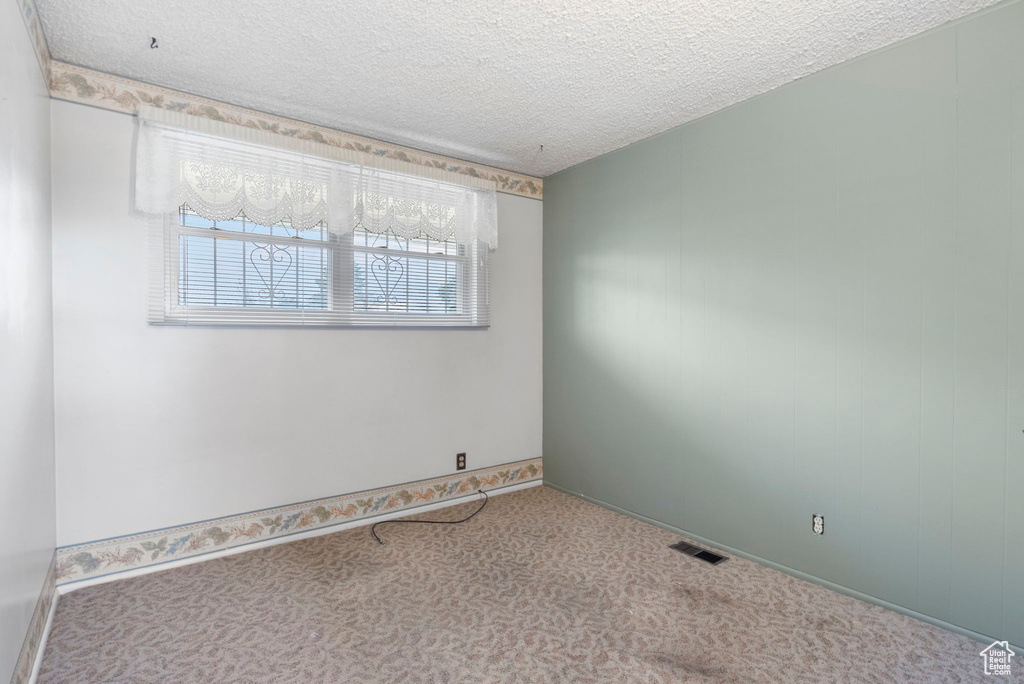 Carpeted spare room featuring a textured ceiling