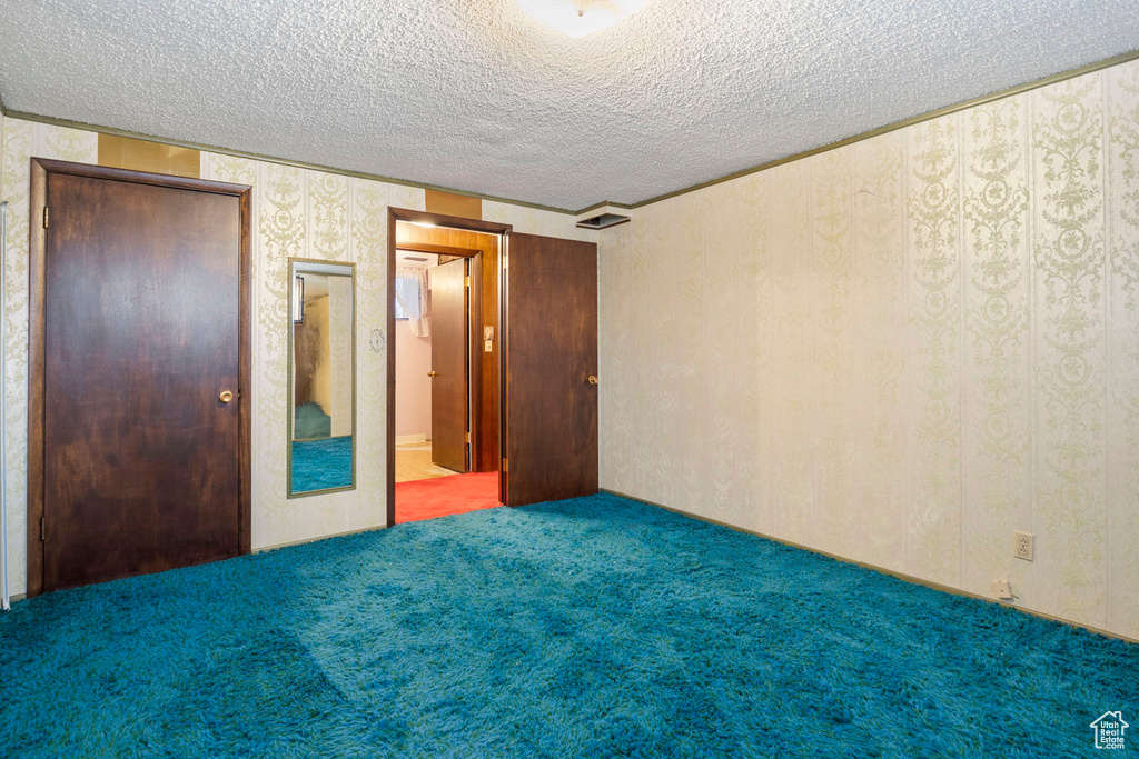 Unfurnished bedroom featuring a closet, carpet, and a textured ceiling