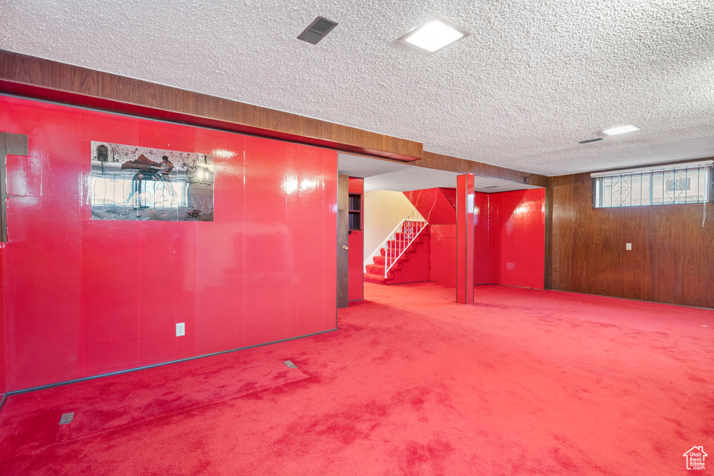 Basement with carpet, wood walls, and a textured ceiling