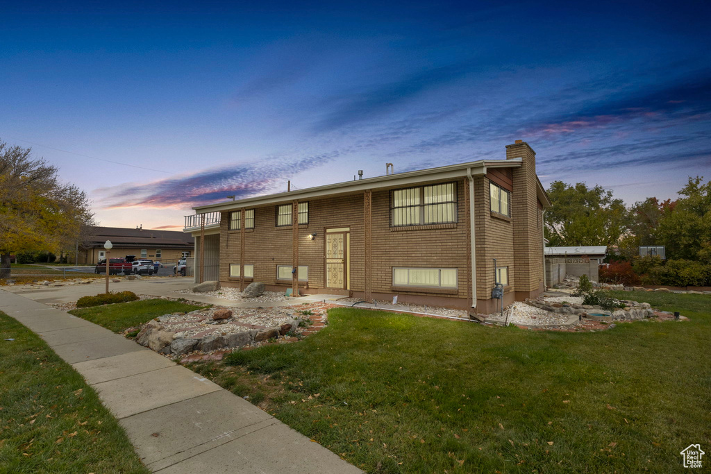 View of front of home with a yard and a balcony