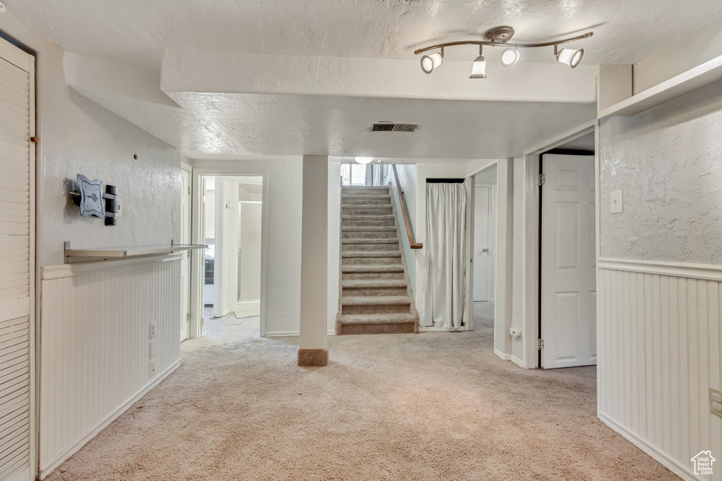 Basement with a textured ceiling and light carpet