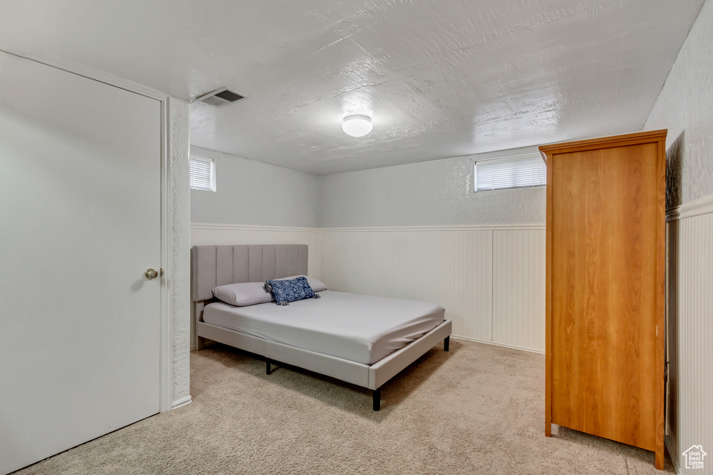 Bedroom with light colored carpet and a textured ceiling