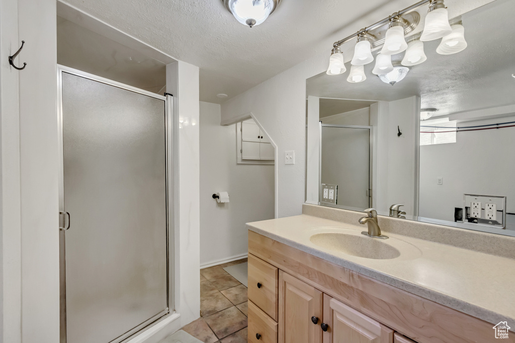 Bathroom with walk in shower, vanity, and a textured ceiling