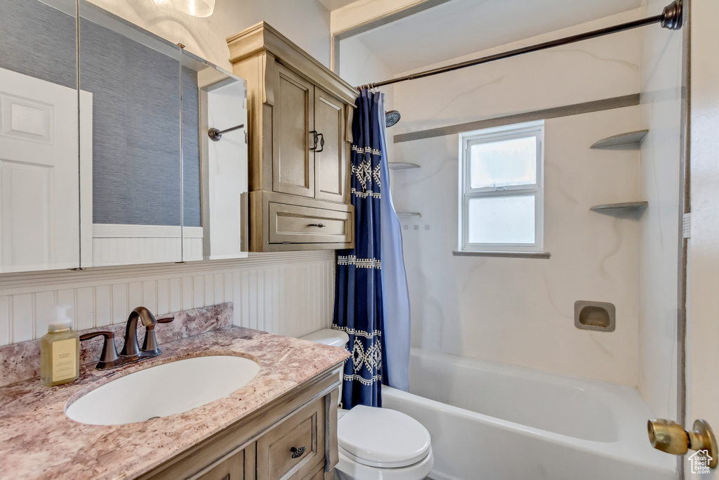 Full bathroom featuring vanity, shower / bathtub combination with curtain, and toilet