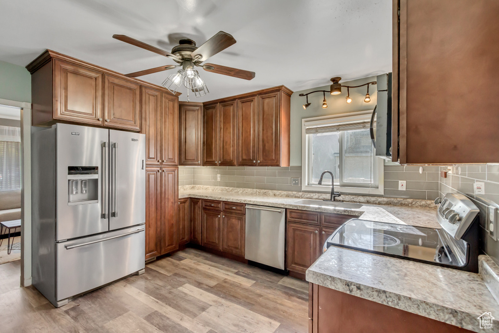 Kitchen featuring light hardwood / wood-style floors, appliances with stainless steel finishes, sink, and backsplash