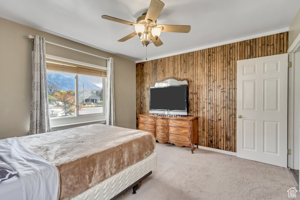 Bedroom with wood walls, ceiling fan, and carpet