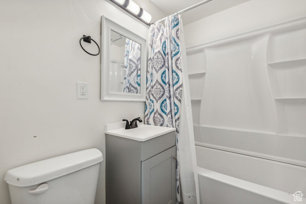 Full bathroom featuring toilet, vanity, and shower / bathtub combination with curtain