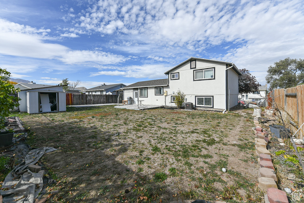 Back of property with a storage unit, cooling unit, and a patio