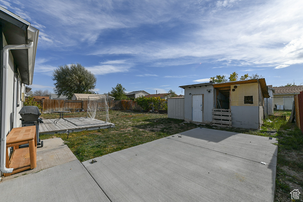 View of yard featuring a patio, a wooden deck, and a storage shed