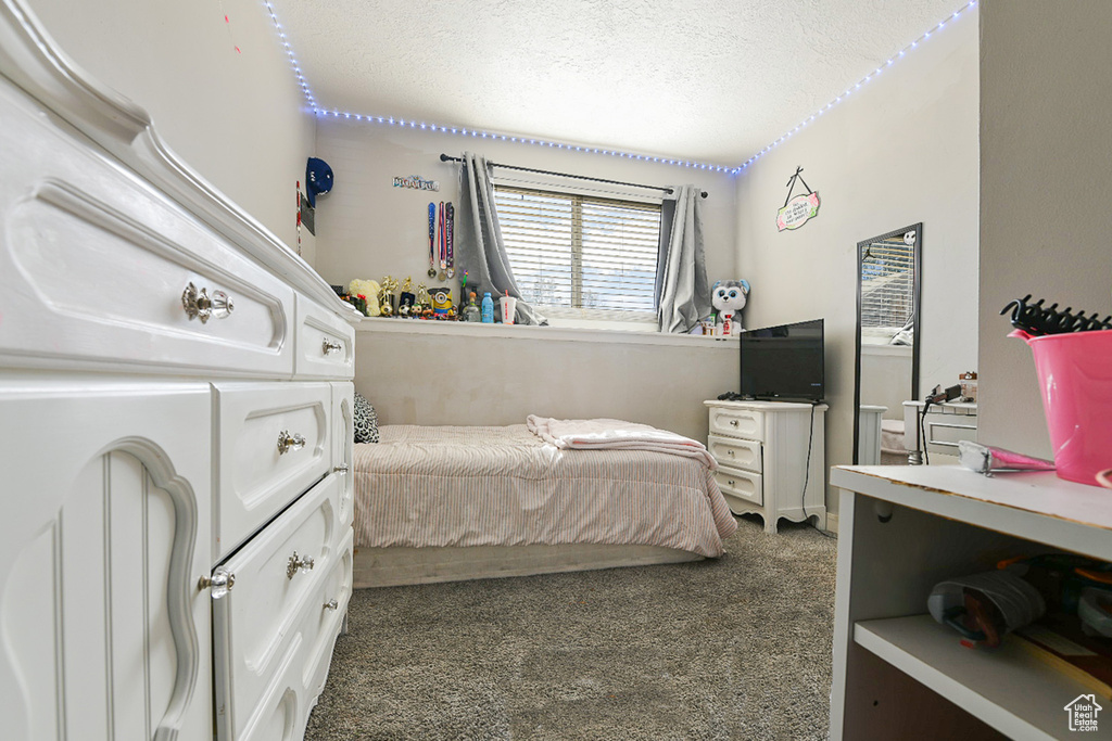 Bedroom with dark colored carpet and a textured ceiling