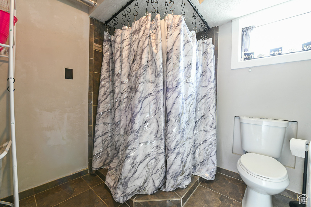 Bathroom with tile patterned floors, toilet, and a shower with curtain