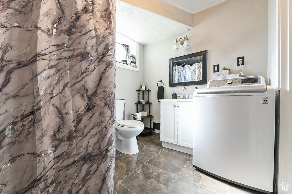 Bathroom with vanity, a textured ceiling, toilet, and washer / clothes dryer