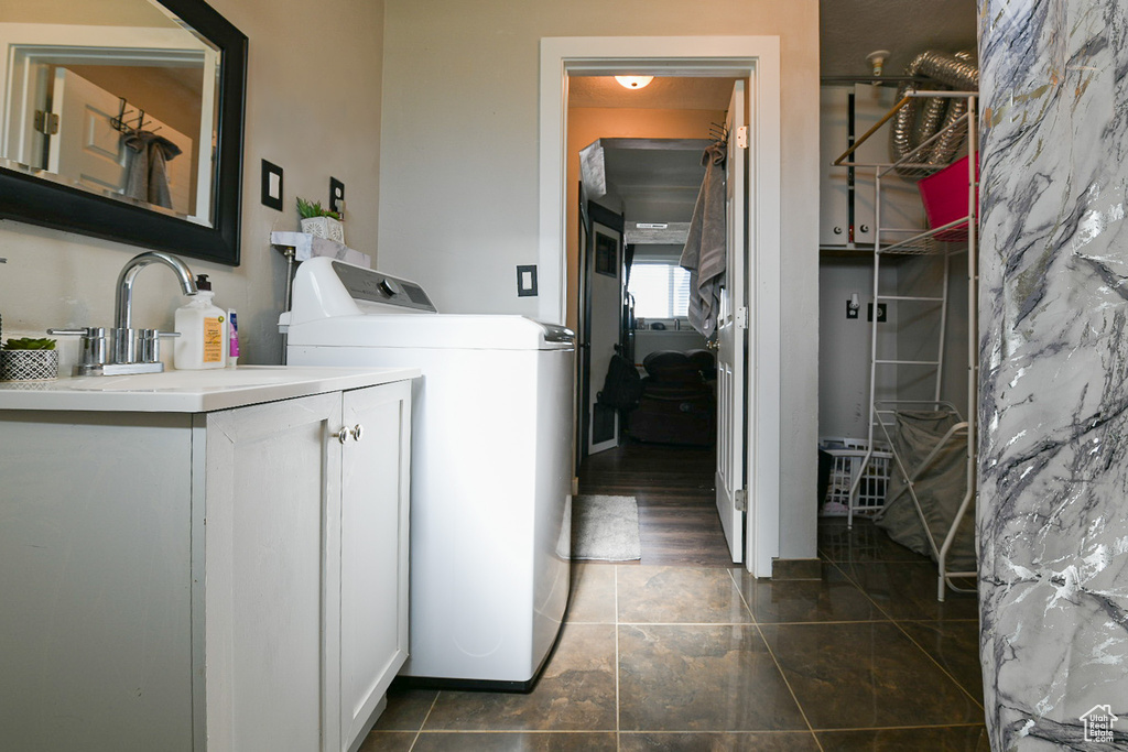 Washroom with dark wood-type flooring, cabinets, sink, and washer and dryer