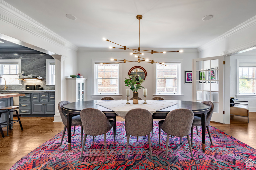 Dining area featuring dark hardwood / wood-style floors, a chandelier, and ornamental molding