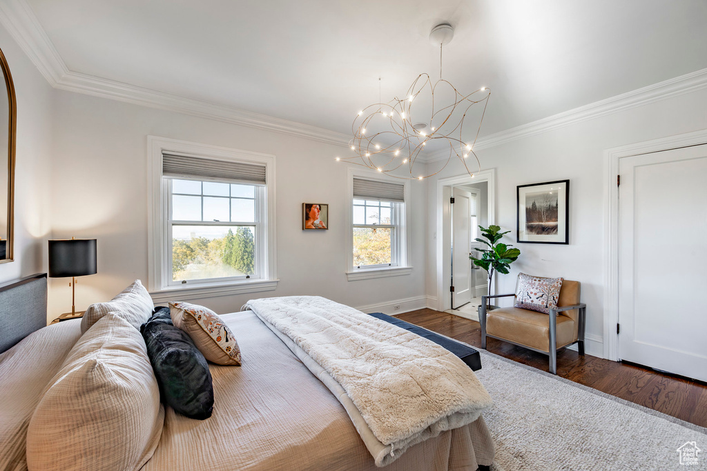 Bedroom featuring dark wood-type flooring, a chandelier, and crown molding