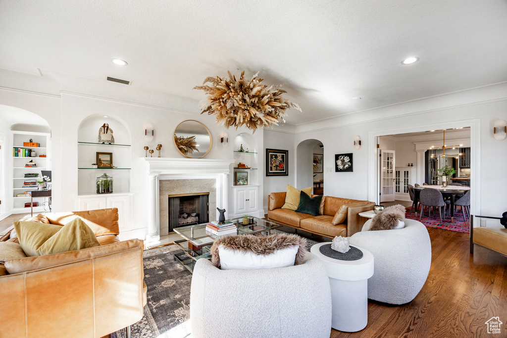 Living room with built in shelves, dark hardwood / wood-style floors, and crown molding