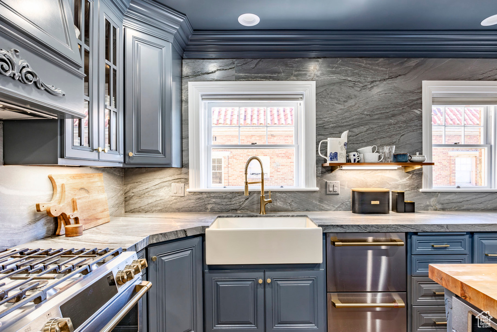 Kitchen with stainless steel stove, decorative backsplash, crown molding, and wood counters