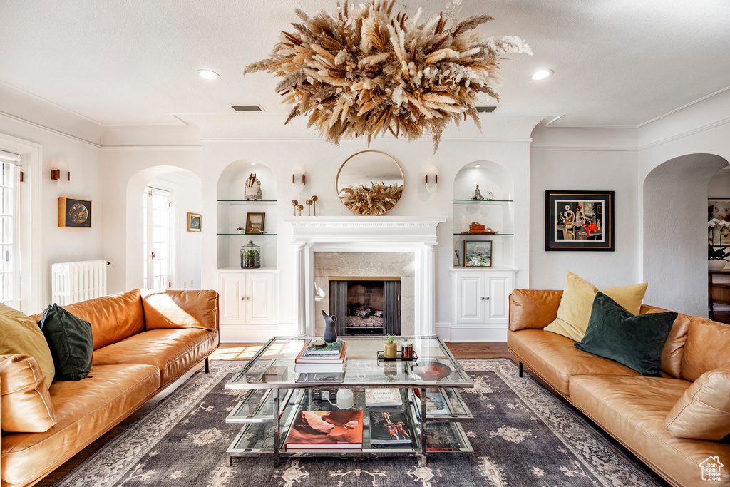 Living room with dark hardwood / wood-style flooring, radiator, crown molding, and built in shelves