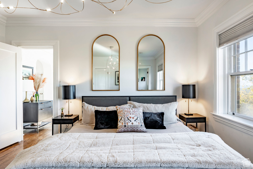 Bedroom with a chandelier, hardwood / wood-style floors, and ornamental molding