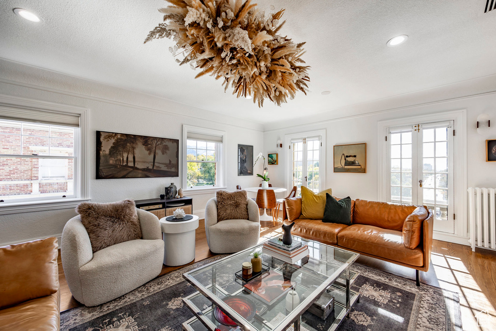 Living room featuring french doors, hardwood / wood-style floors, radiator heating unit, and a textured ceiling