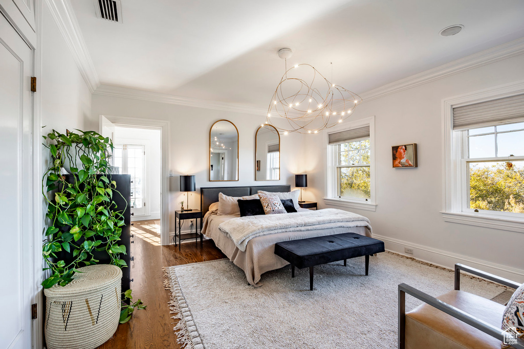 Bedroom featuring dark hardwood / wood-style flooring, an inviting chandelier, and ornamental molding