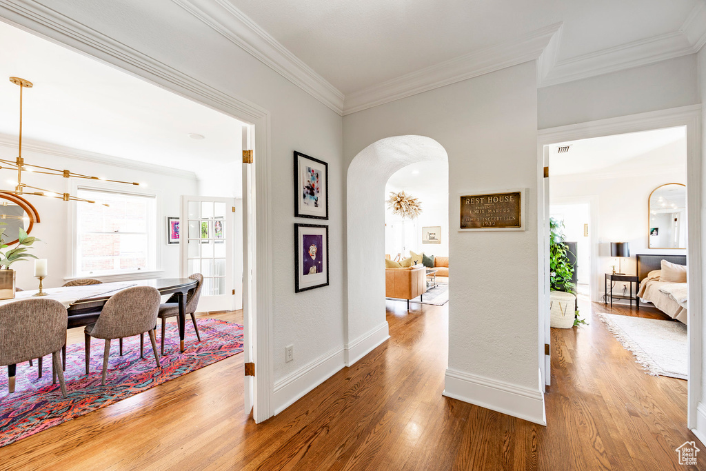 Hall with a chandelier, hardwood / wood-style floors, and ornamental molding