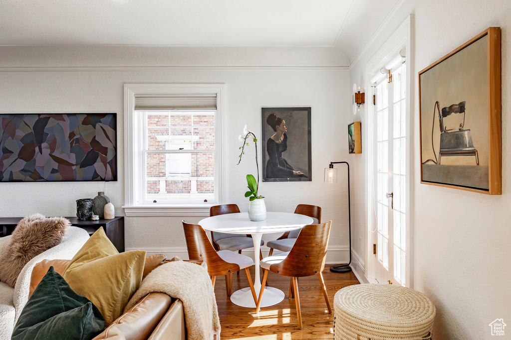 Dining space with ornamental molding and hardwood / wood-style flooring