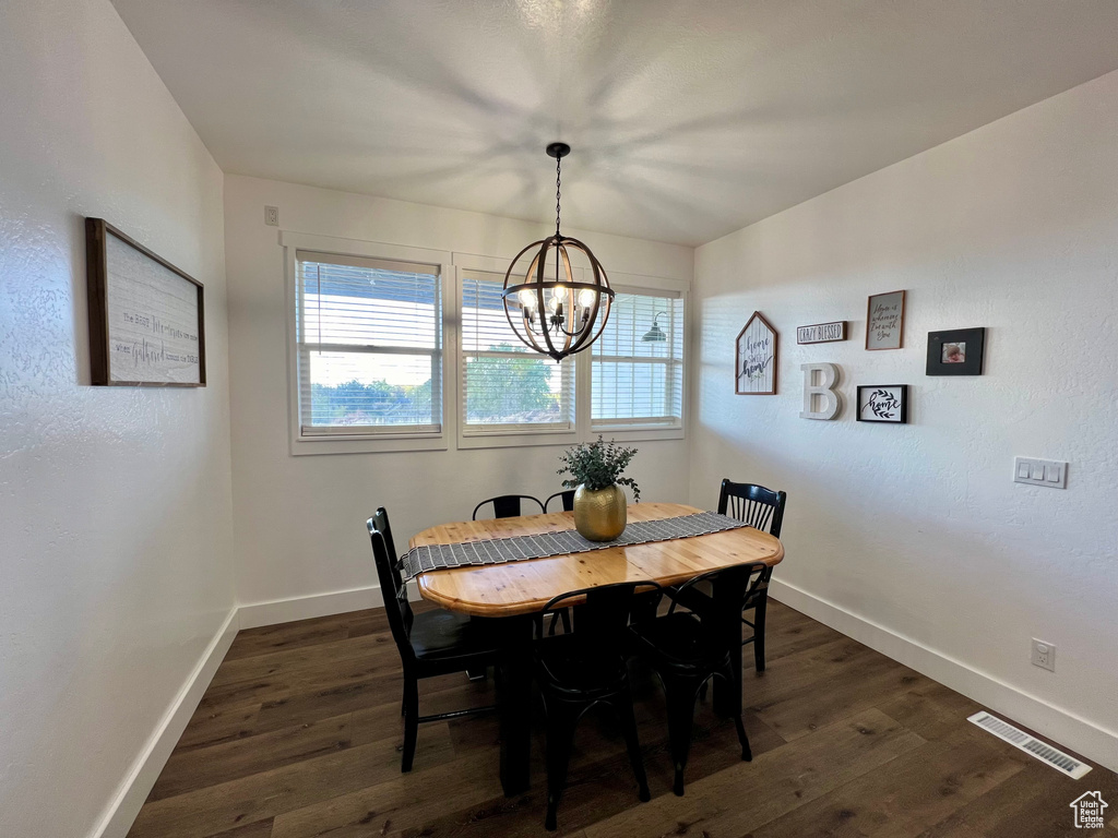 Dining space with dark wood-type flooring and an inviting chandelier