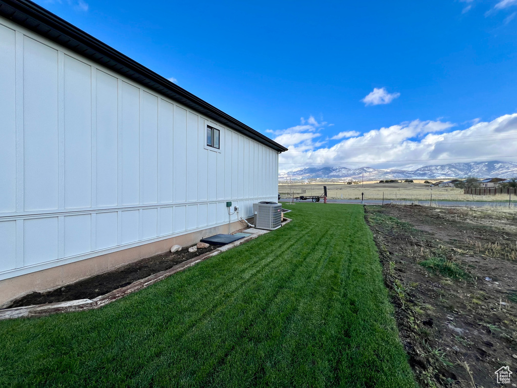 View of side of property featuring central air condition unit, a mountain view, and a lawn