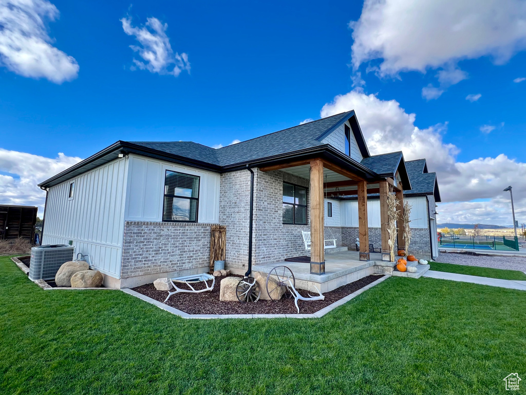 Rear view of house with central air condition unit, a patio area, a swimming pool, and a lawn