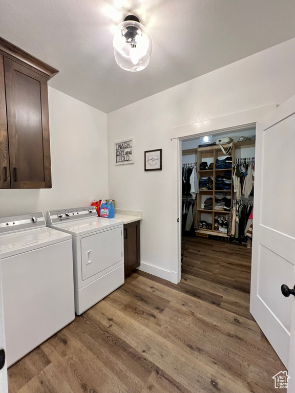 Washroom with cabinets, hardwood / wood-style flooring, and washing machine and clothes dryer