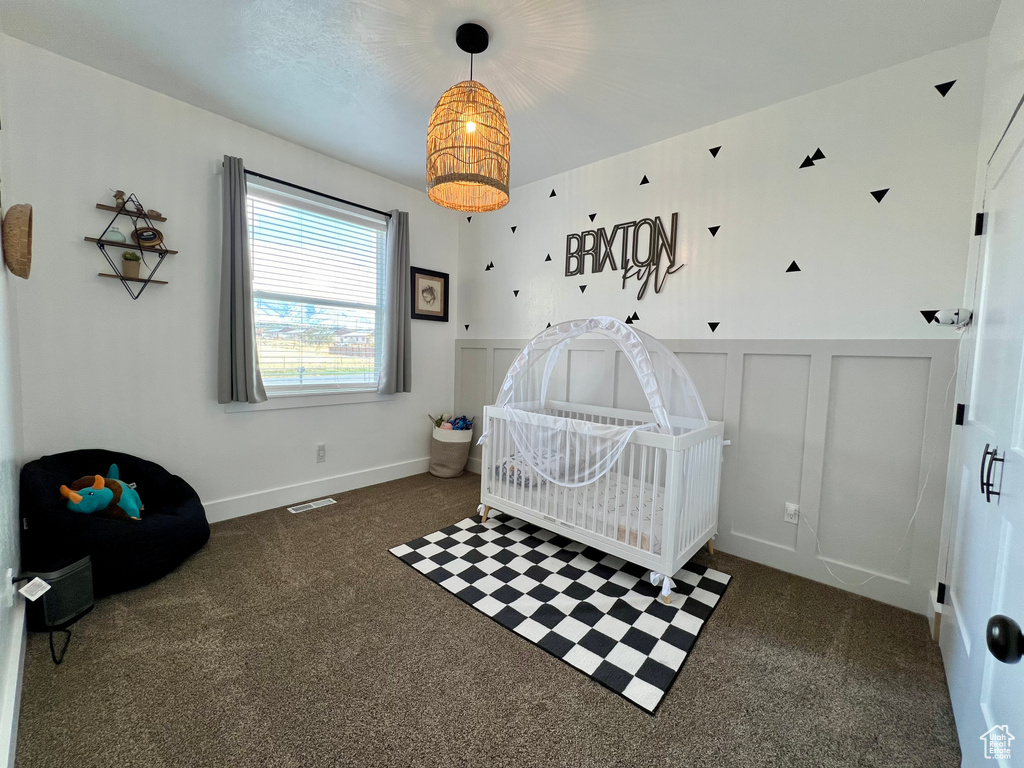 Bedroom with a crib and dark colored carpet