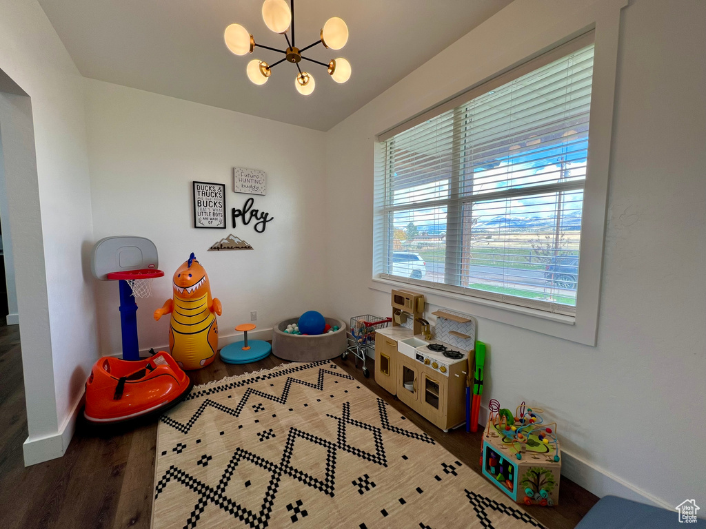 Game room featuring dark wood-type flooring and a notable chandelier