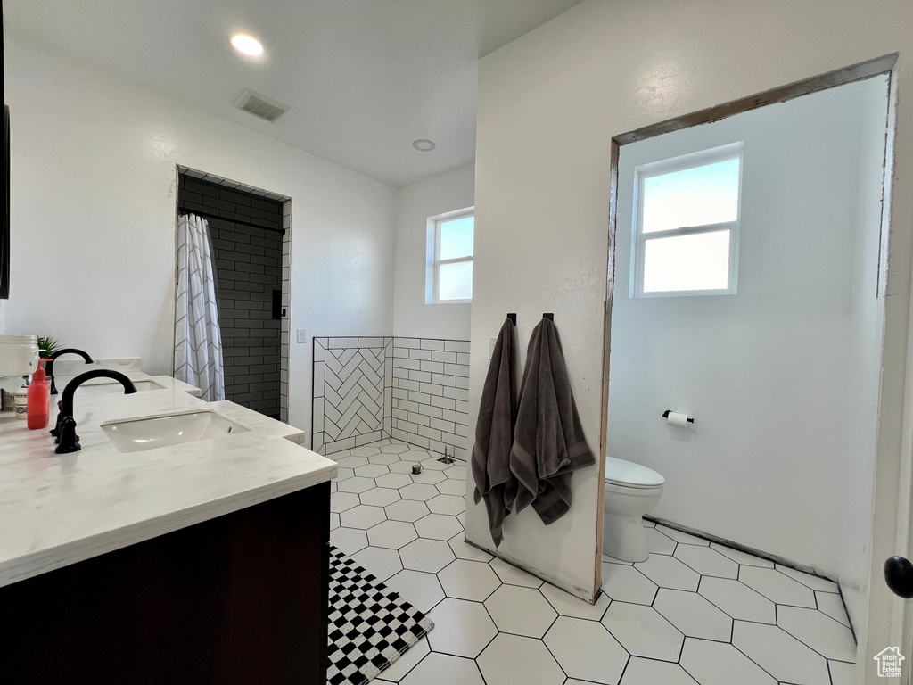 Bathroom with toilet, a healthy amount of sunlight, vanity, and a shower with shower curtain