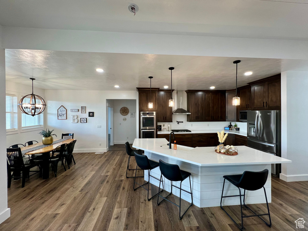 Kitchen with appliances with stainless steel finishes, dark hardwood / wood-style floors, and hanging light fixtures