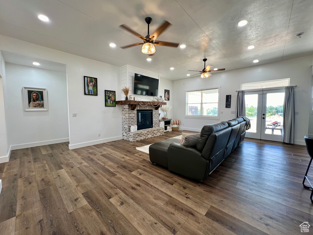 Living room with french doors, a brick fireplace, dark hardwood / wood-style floors, and ceiling fan